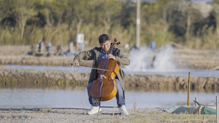 卢建君在养殖塘边拉琴（央广网记者  俞烨  摄）