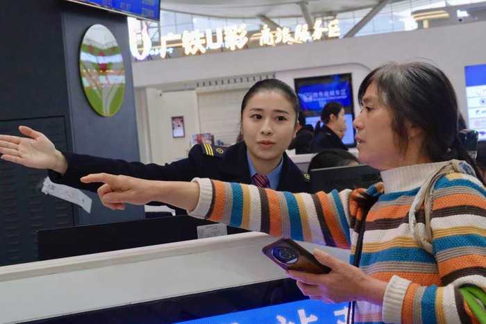 图为深圳北站，“迎春花”服务队工作人员在回答旅客问询。郑雨馨摄