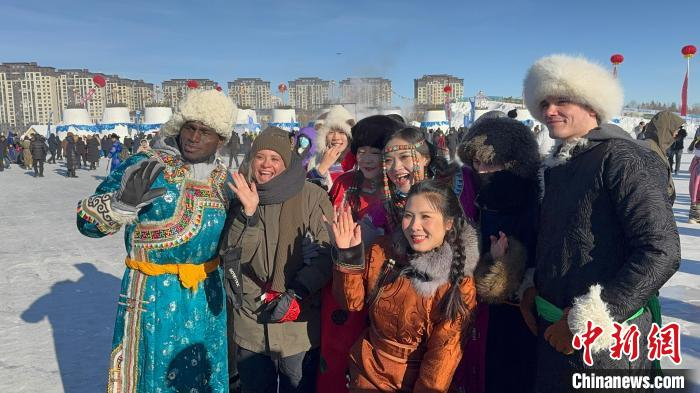  图为外国游客身着传统蒙古袍，与当地民众合影留念。奥蓝 摄