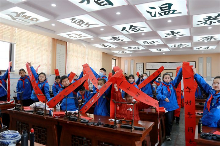 湖北省书法协会会员杨明银老师指导学生学书法写春联。