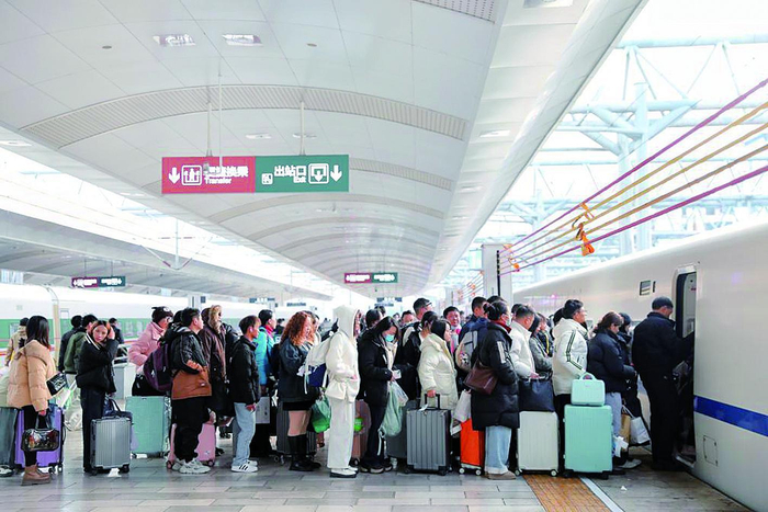     昆明火车站站台上，安全绳升起，旅客排队上车。