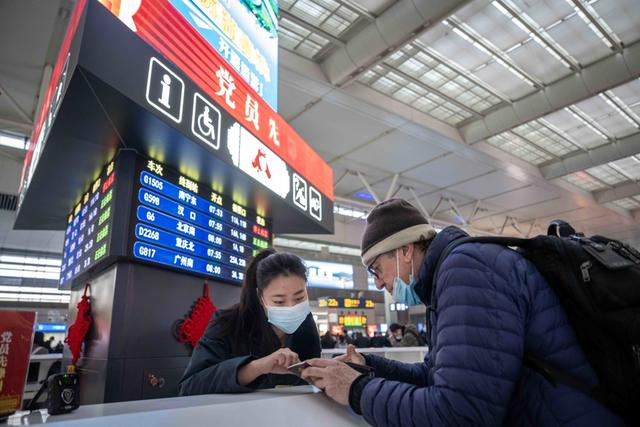 今年更多外籍游客加入“春运大军”，图为虹桥站工作人员解答外籍旅客的疑问。