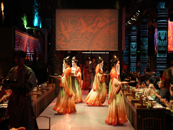 身着汉服的工作人员正在为顾客们上菜。