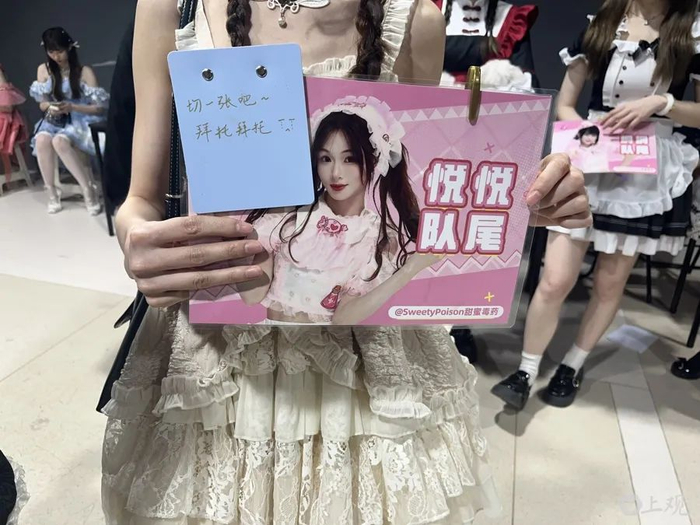 1月4日特典会上，“甜蜜毒药”的成员悦悦拿着自己的合影“队尾”牌子。王倩 摄