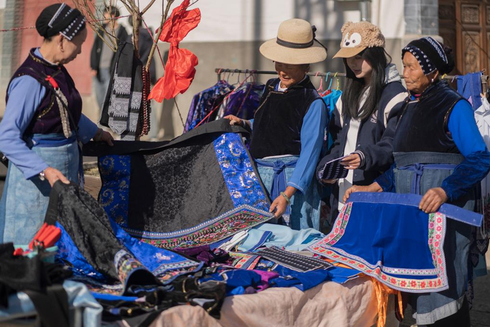 近日，在云南省大理白族自治州洱源县凤羽古镇年集上，当地村民挑选新衣。新华社发（罗新才 摄）