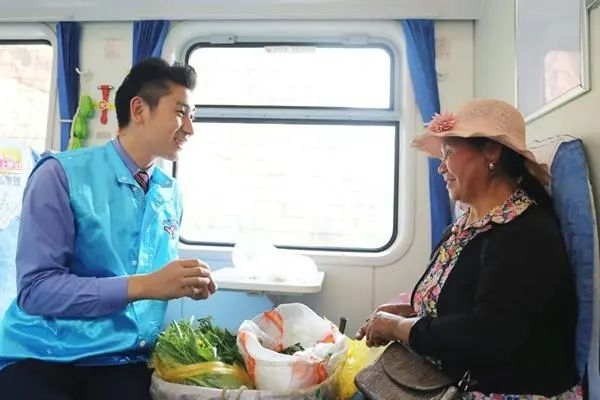 1月22日，昆明至红果的5652次“共青团号”公益慢火车上，昆明客运段青年志愿者周学党（左）帮助老乡整理蔬菜。冯俊/摄