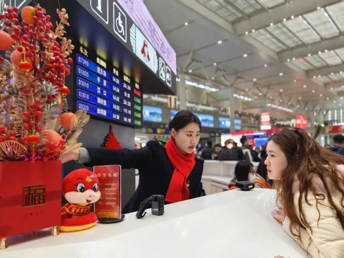 上海虹桥站客运值班员刘雅婷在服务台引导旅客前往检票口。