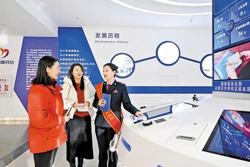     1月26日，石家庄市桥西区税务局工作人员（右一）向企业办事员讲解研发费用加计扣除税收优惠政策。本报记者 张 昊摄