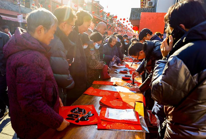 2025年1月10日，武汉，柏泉茅庙集庙会上，人们写春联。
