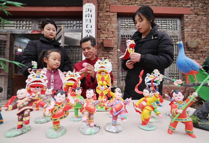 2025年1月30日，山东省临沂市，非物质文化遗产代表性项目左氏面塑代表性传承人左安胜（中）在新春庙会上制作面塑。