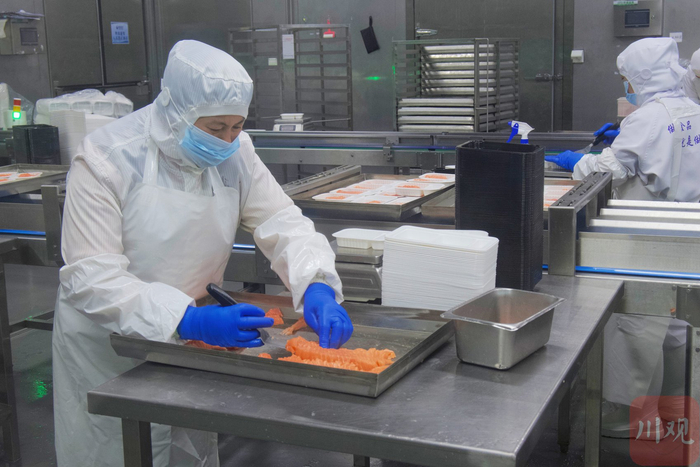 西部生鲜港的三文鱼智能加工工厂内，工人们正在分装切好的三文鱼。