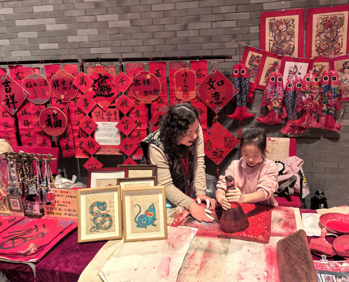 “过年——春节主题展”现场，观众正在体验杨家埠木板年画。（受访者供图）