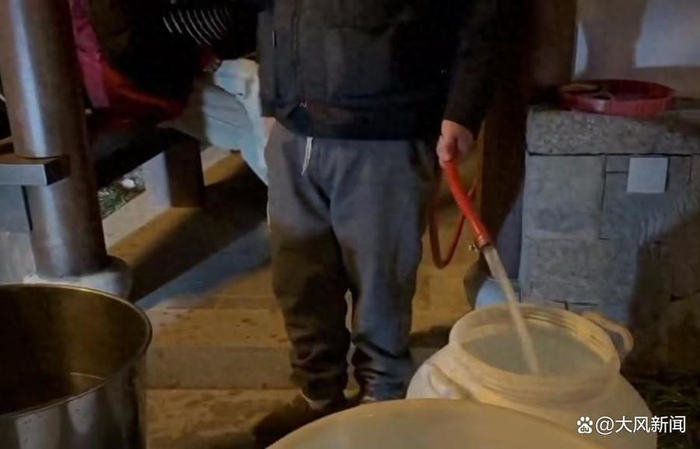 一黑衣男子正用一根红色的水管接水