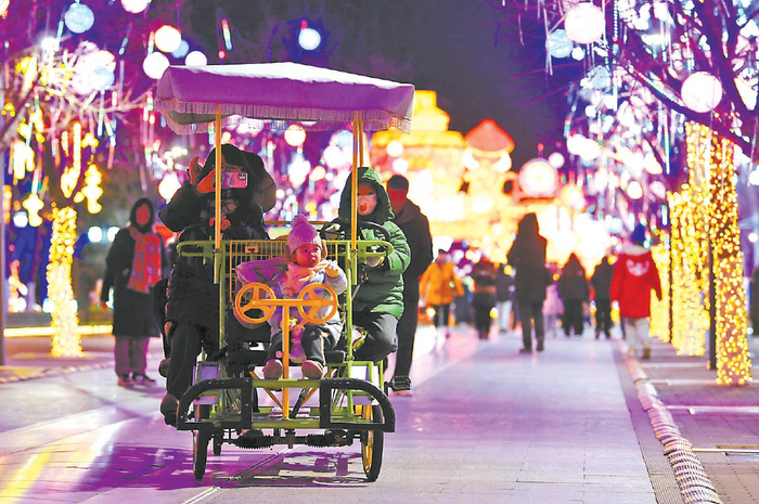 游客在北京世园边骑车边赏灯 摄影/本报记者 袁艺