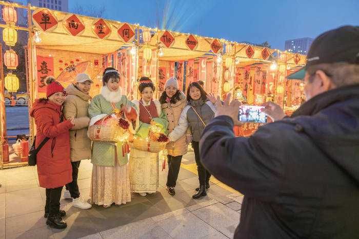 2月11日傍晚，门头沟区2025年元宵节国潮市集开幕。图为市民与身着传统服饰的工作人员合影。新京报记者　王子诚　摄