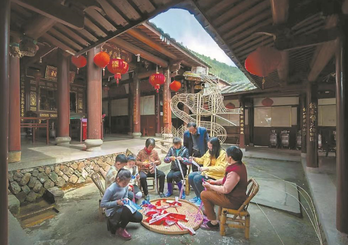 男女老少一起剪龙鳞纸花。林跃 摄