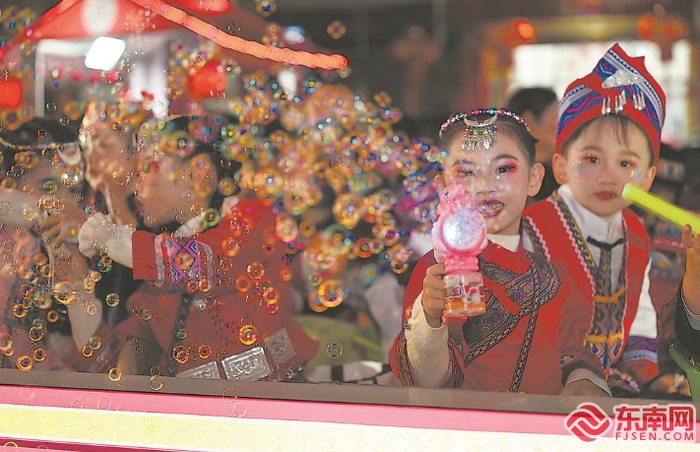 一辆“民族一家亲”主题的彩车上，身着少数民族服装的孩子与观众互动。福建日报记者 施辰静 摄