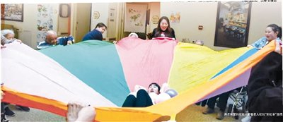 养老院里的年轻人带着老人们玩“彩虹伞”游戏