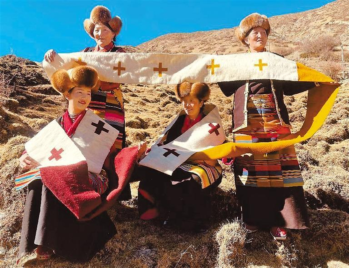     合作社女工展示编织好的藏式手工艺品。