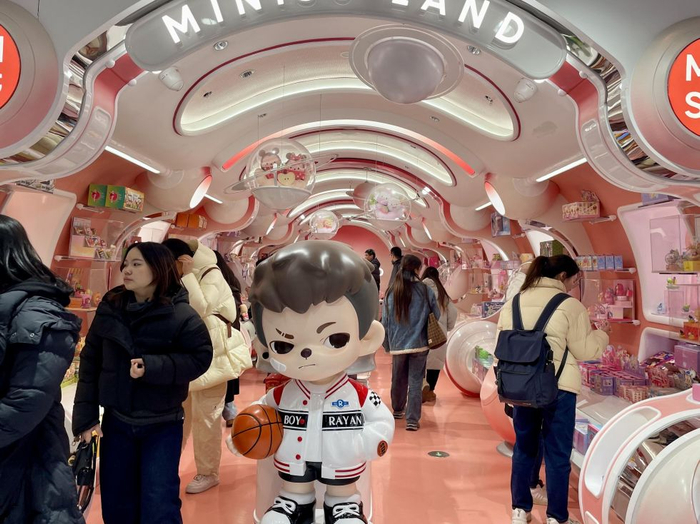 游客在上海南京东路的名创优品首家全球级MINISO LAND壹号店选购周边手办。新华社记者 周杉 摄