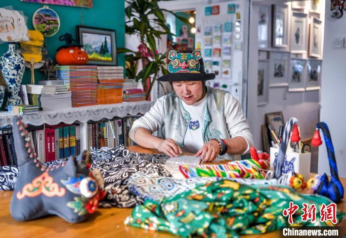 2月20日，新疆乌鲁木齐市倾城布老虎文创工作室，马秀玲在艾德莱斯绸上进行布老虎制作中的打板工作。中新社记者 刘新 摄