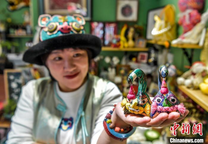 2月20日，新疆乌鲁木齐市倾城布老虎文创工作室，马秀玲展示使用艾德莱斯绸制作的布老虎。中新社记者 刘新 摄