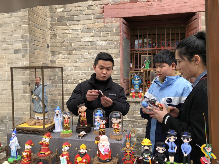 在市区花戏楼景区，梁岗子正在向游客介绍哪吒相关面塑。