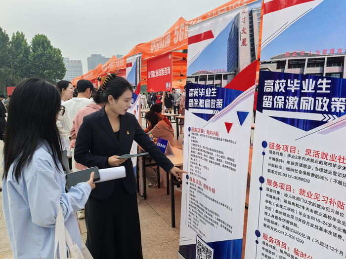 市人社局组织招聘会，工作人员为毕业生讲解留保激励政策。 受访单位供图