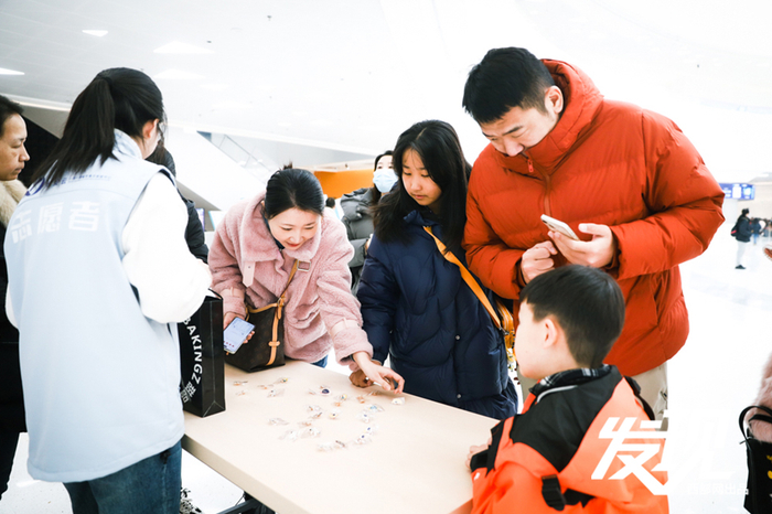 志愿者在科技馆大厅为前来参观的游客分发科学小奖品，提供丰富的文化体验。