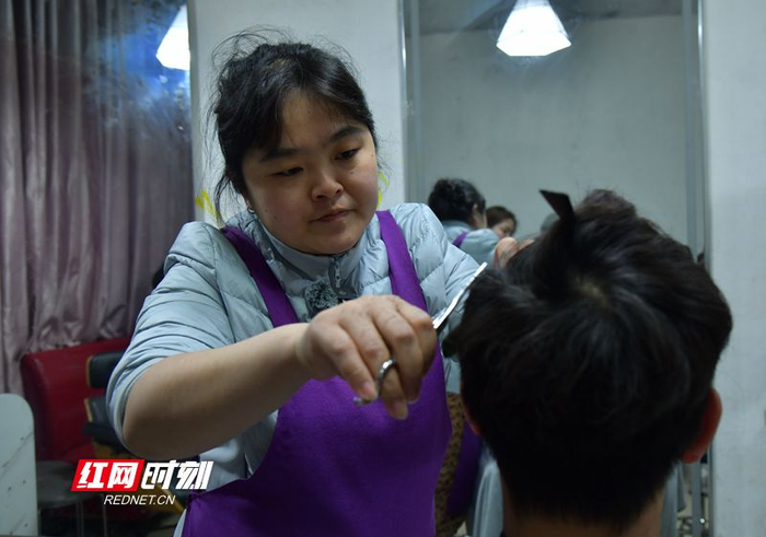 李晓华在给顾客剪头发。