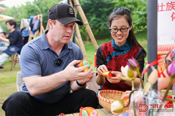 　　▲2024年广西三月三期间，外国游客在体验绣球制作。自治区文化和旅游厅供图