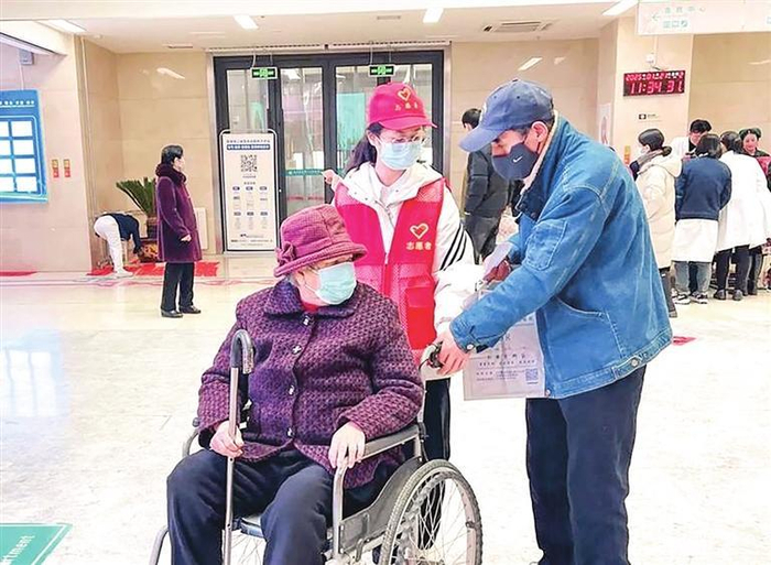 志愿者帮助行动不便的患者。兰州新区报记者姜波 摄