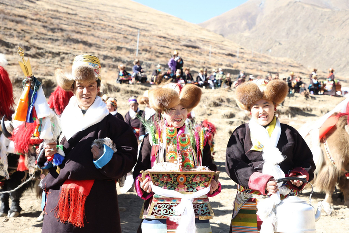 图为开耕仪式现场手捧切玛、青稞酒的年轻男女