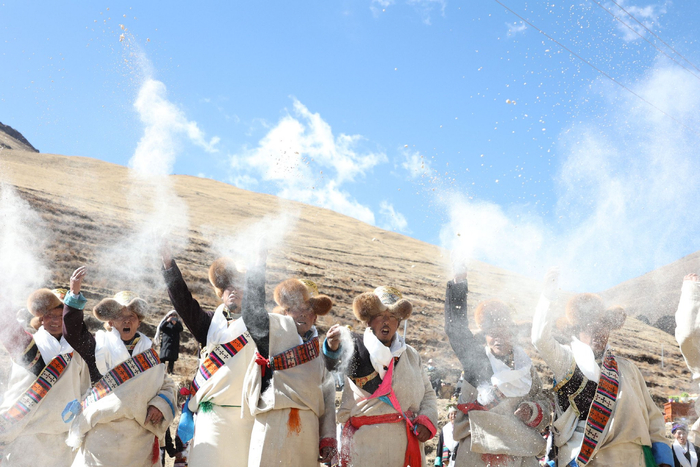 图为村民们抛洒糌粑送祝福