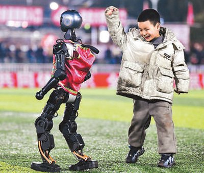 2025年贵州“村超”40强交叉赛现场，小朋友与机器人互动。新华社记者 杨文斌摄