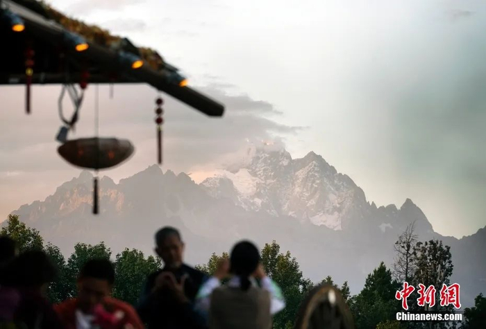  图为游客在丽江古城高点远眺玉龙雪山。中新社记者 侯宇 摄