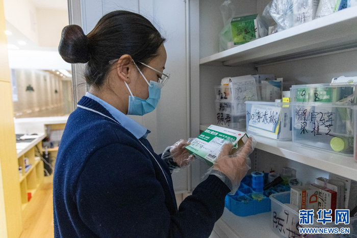   李丽萍检查整理老人们的日常用药（3月18日摄）。新华网 李浩 摄