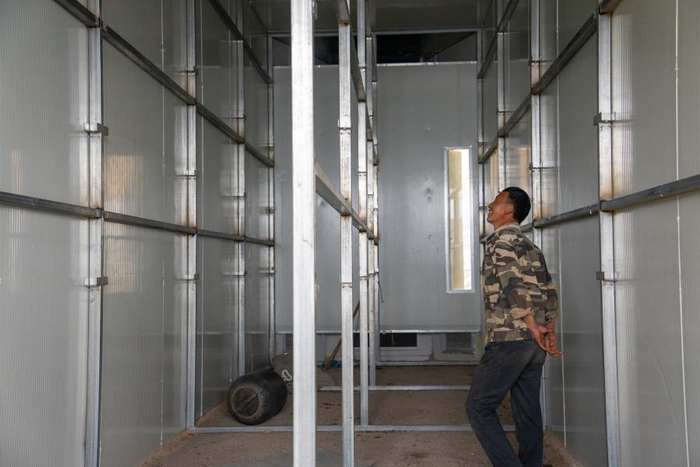 李林军在查看他管理的电能烤房（3月13日摄）。杨荣辉 摄