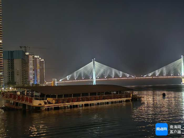 海口湾夜幕下的倾斜搁浅“餐饮船”。记者 叶长文 摄