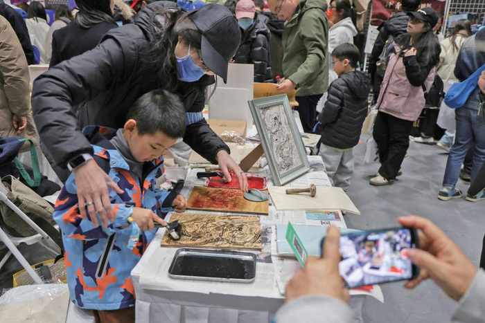 3月29日，新京报书评周刊摊位，小朋友体验传统木版印刷。新京报记者 王远征 摄