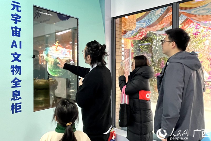 游客通过AI文物全息柜了解广西铜鼓。人民网韦欢摄