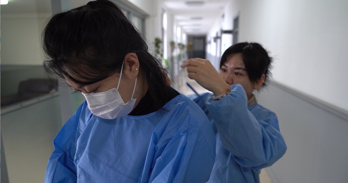 同事帮何宇辰穿防护服（央广网发  孙旭  摄）