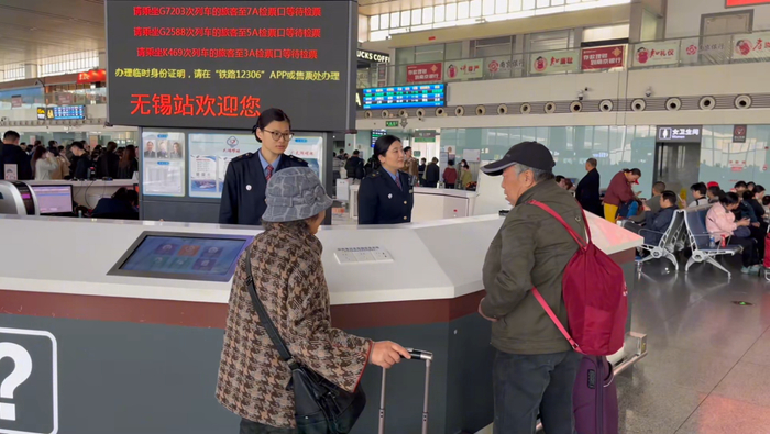 无锡站工作人员为银发旅客解答引导。高鹏 供图