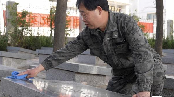 今年清明节前夕，退伍老兵张景宪为无名烈士擦拭墓碑。