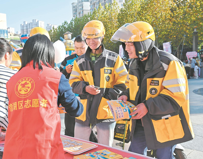 芜湖市志愿者为新就业群体代表发放爱“新”商户服务卡和服务券。（资料图片） 芜湖市镜湖区委社会工作部供图