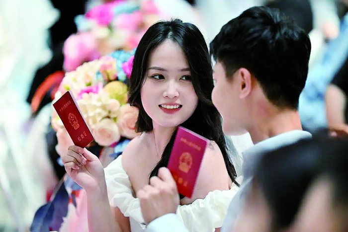     一对新人手拿结婚证留影 新华社发