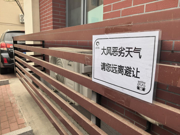 ▲4月11日，北京一小区外墙立面贴上了大风警示标语。图据视觉中国