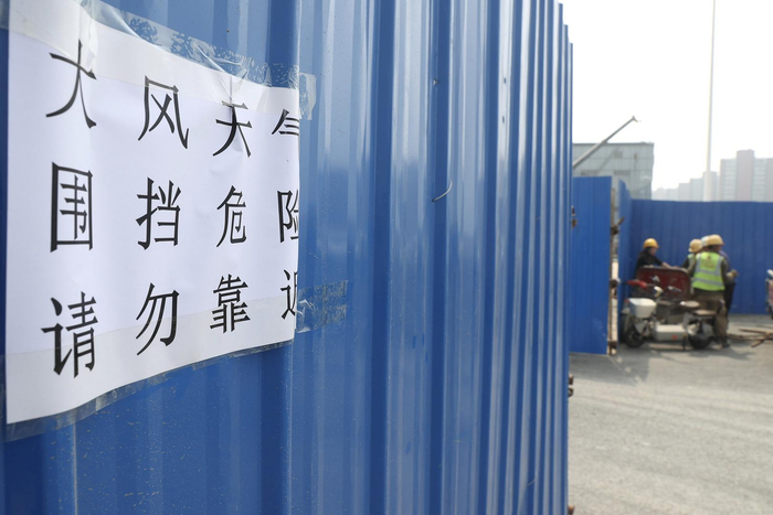 ▲4月11日，北京通州通胡大街加华印象街小区在加固楼房外立面，防止大风吹落并粘贴提示语。图据视觉中国