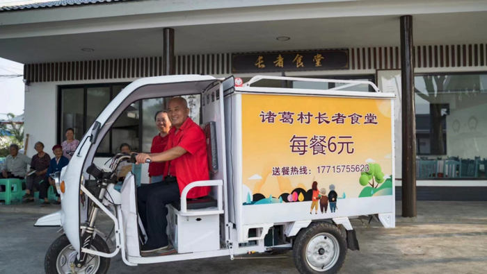 图：杨永东正从“长者食堂”出发，为60岁以上老人送餐到户。
