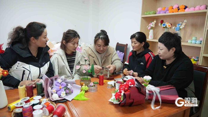 张玉花（中）教学员编织手工艺品。